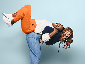 Zwei Freundinnen nehmen einander Huckepack und lachen dabei.