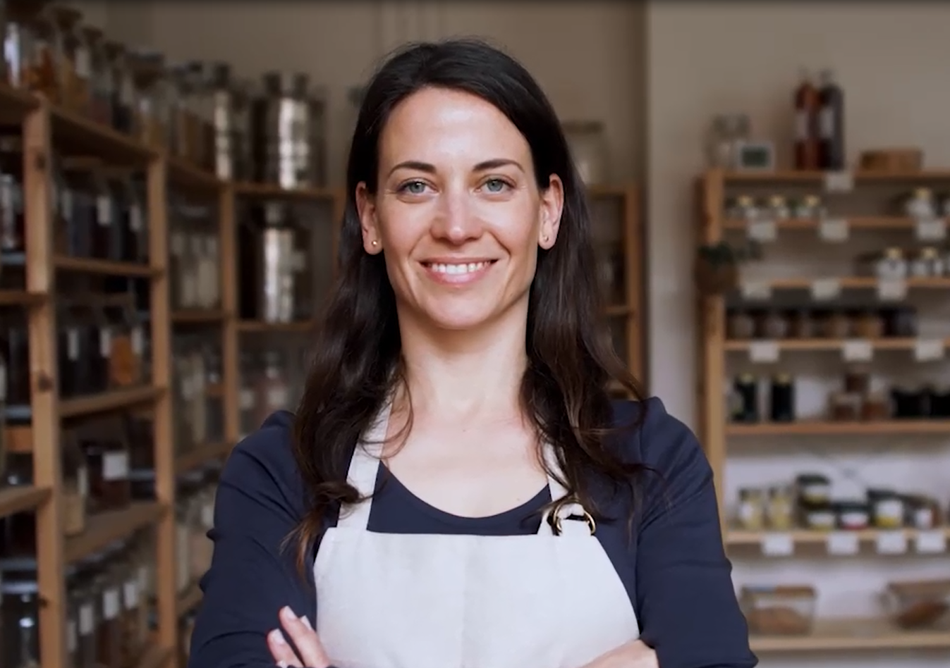 Eine Frau in einem Tante Emma Laden lächelt in die Kamera.