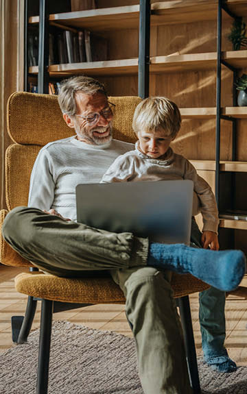 Opa hält seinen Enkel und liest mit ihm ein Buch
